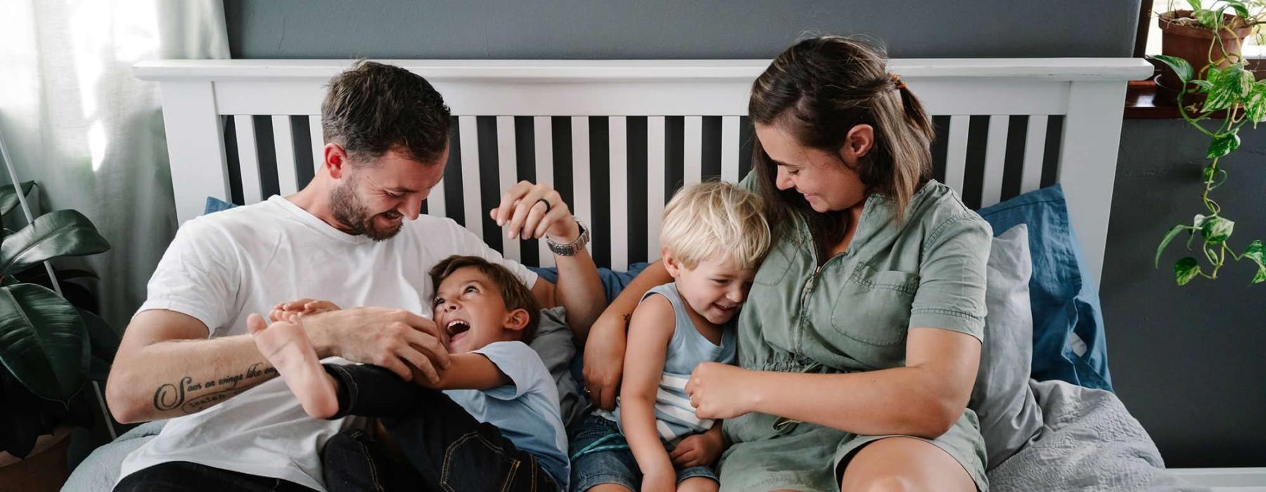 parents play with their children on a bed